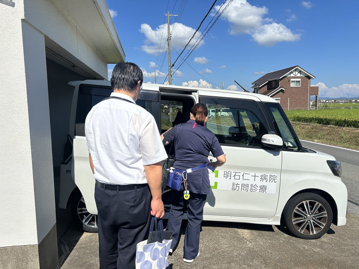 患者宅に到着し車から器材を降ろす医師と看護師