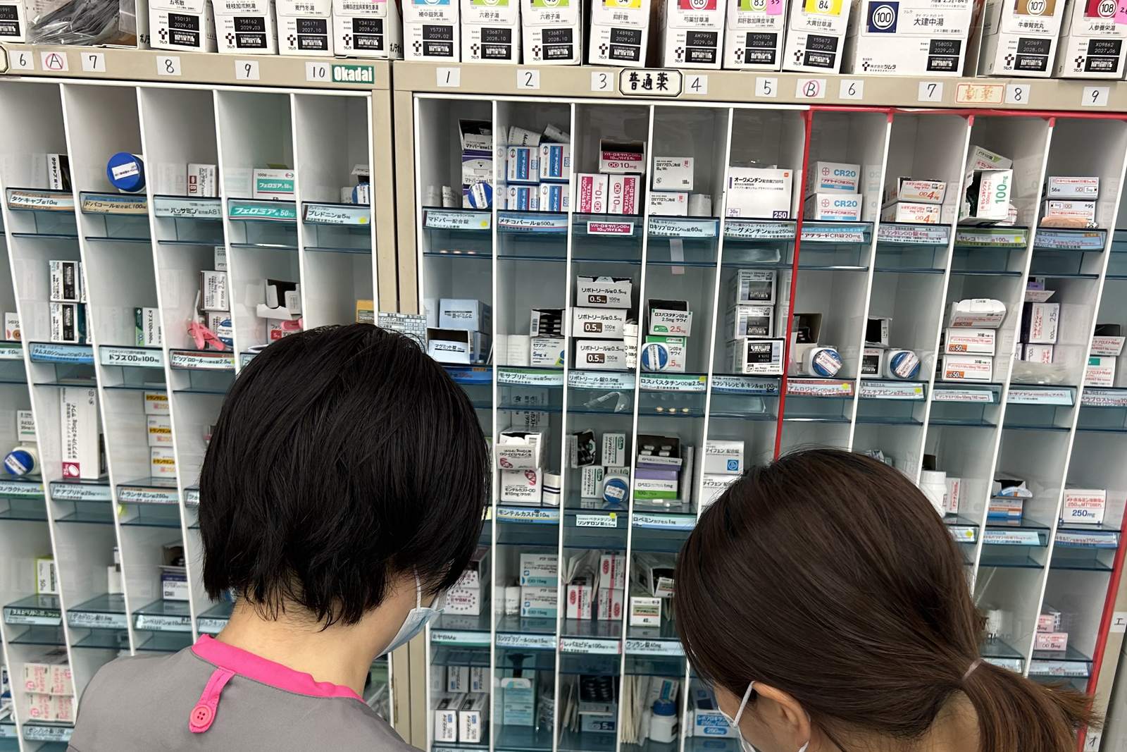 調剤棚の前で薬剤を確認する薬剤部のスタッフ